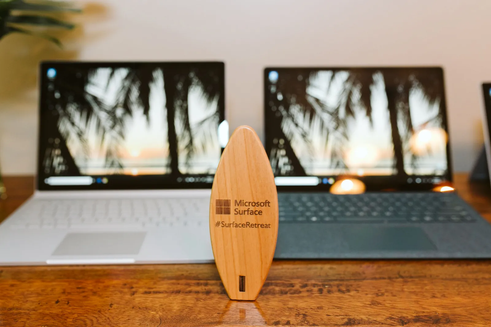Wooden surfboard-shaped Microsoft Surface tech gift in front of two laptops