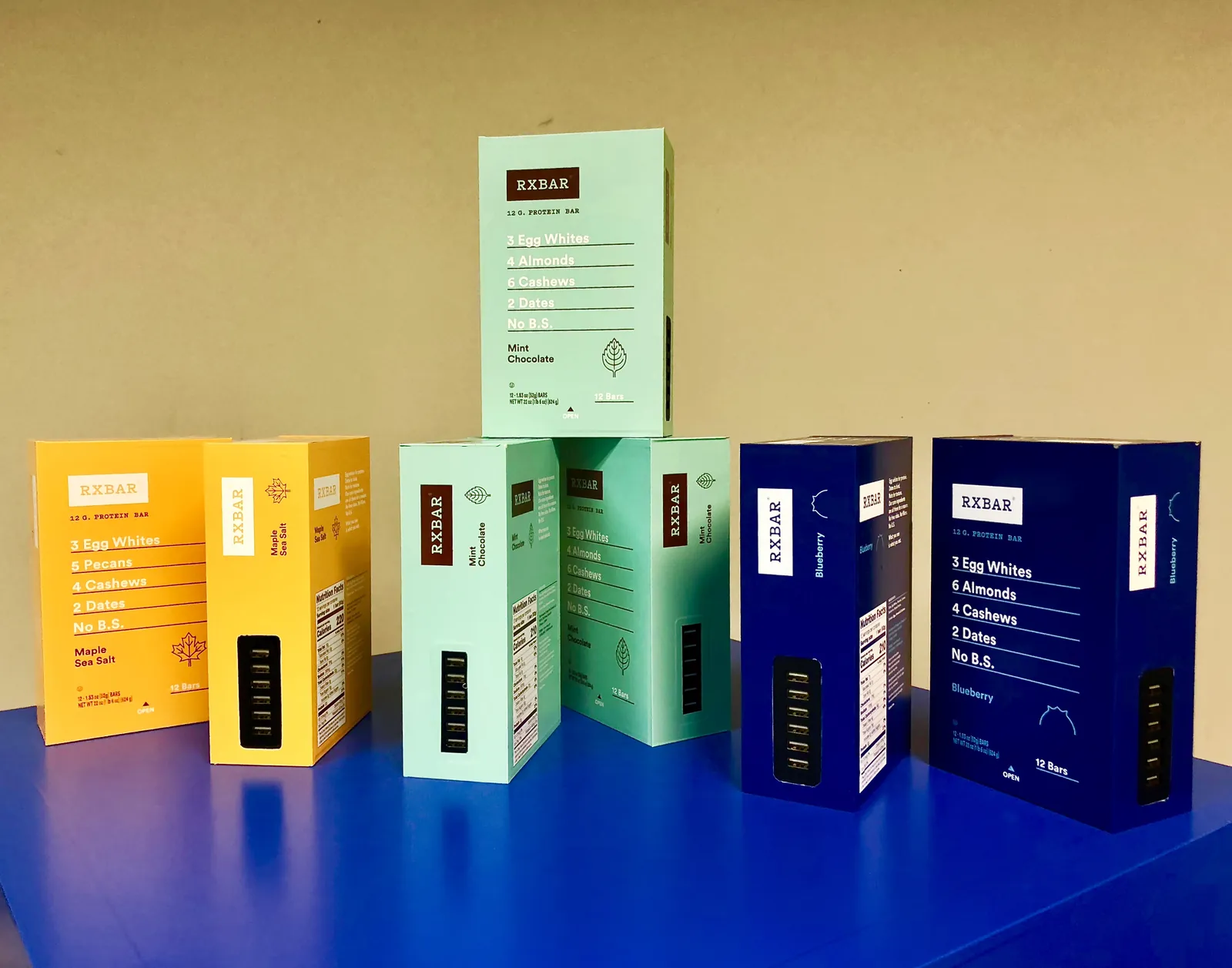 Colorful RXBAR-shaped power banks with visible USB ports on a blue surface