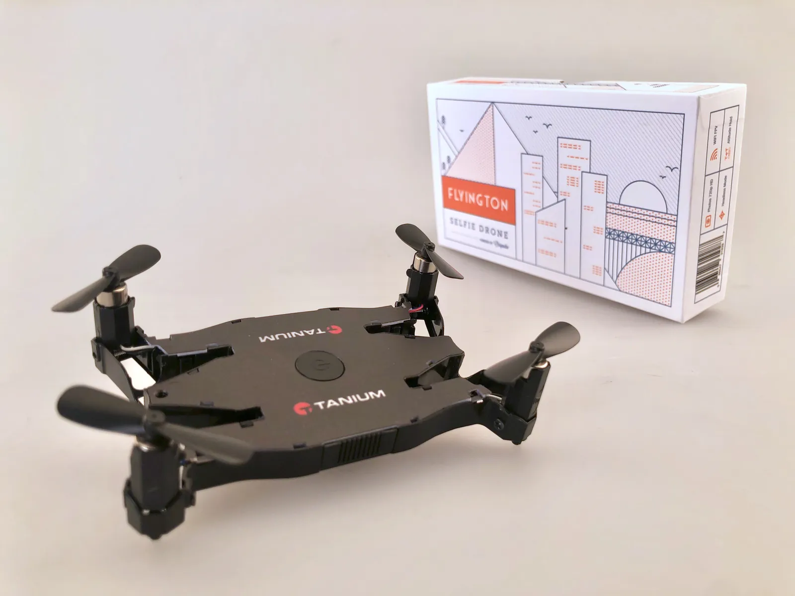Compact black Tanium drone beside its illustrated presentation box